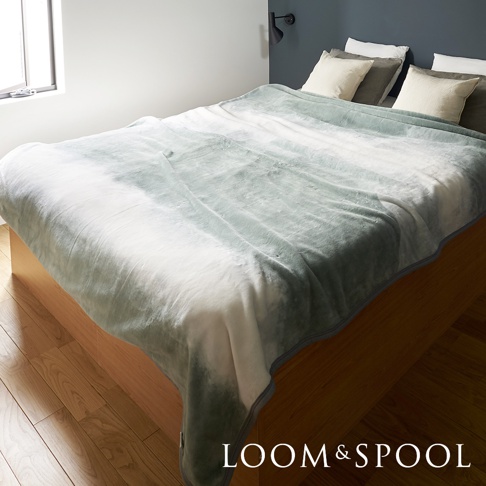 抗菌短絨舒柔雙人毯，採用乳白色與淺綠色漸層的「Flood of Light」花紋，材質觸感柔軟，覆蓋在木質床架上，搭配床頭的兩個淺色枕頭。