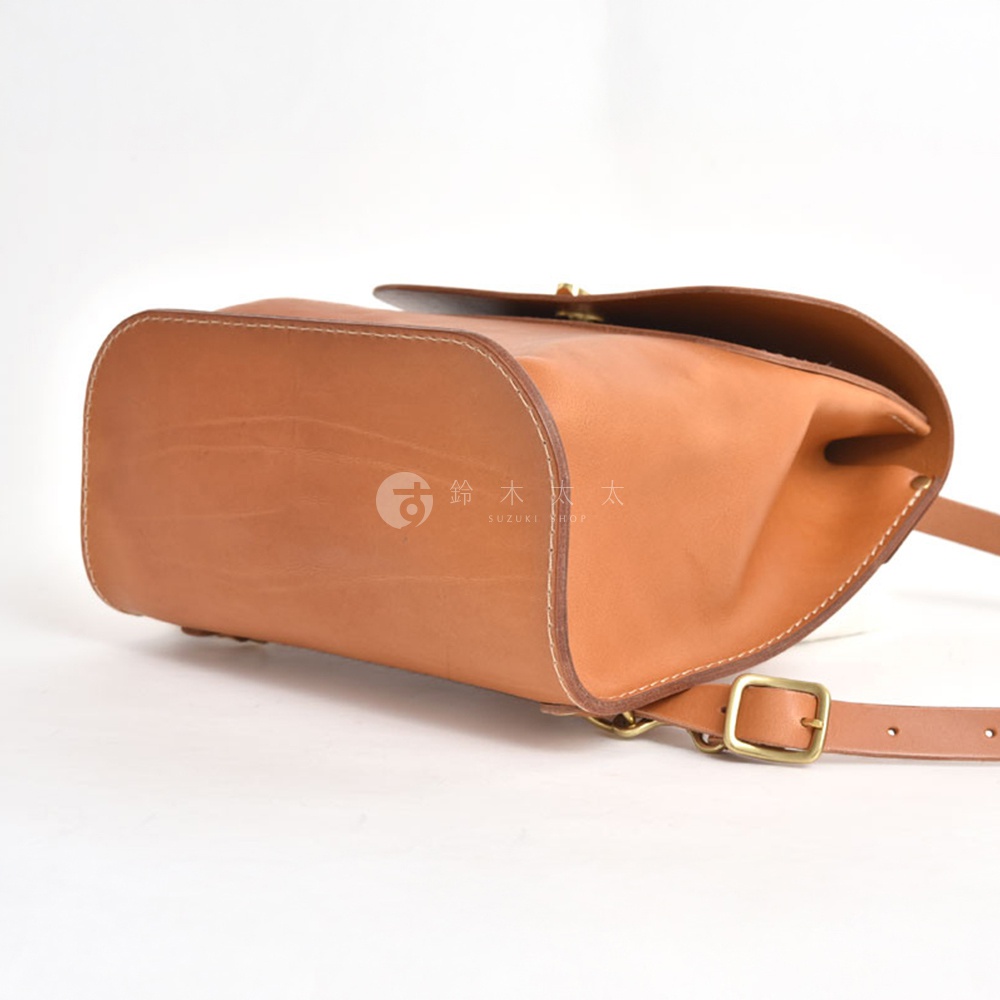 職人手作皮革翻蓋迷你後背包，展示經典棕色皮革，帶有黃銅色扣環和可調式肩帶。