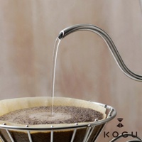 日製 18-8 不鏽鋼極細口咖啡手沖壺，細長壺嘴優雅彎曲，正在將水流精準地注入盛有咖啡粉的濾紙中。