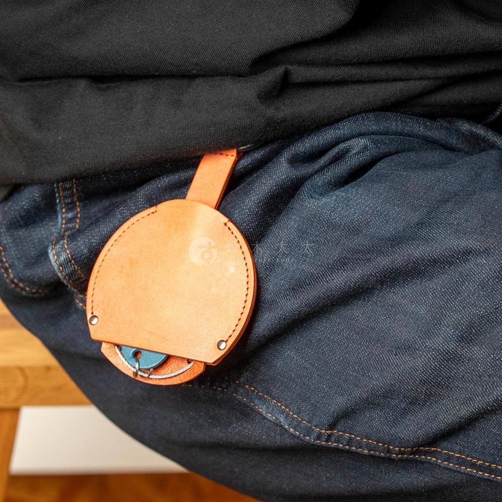 FABRIK 皮革圓形收納鑰匙圈掛在深色牛仔褲的腰帶上，可以看到藍色鑰匙。