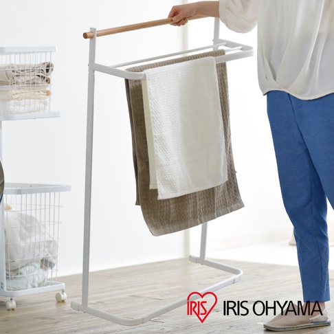 白色金屬框架搭配原木橫桿的毛巾架，掛有兩條不同紋理的毛巾，一條為白色，另一條為棕色。