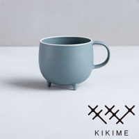 一個藍灰色的美濃燒馬克杯，帶有圓潤的球形杯身和三個支腳。杯口內緣有白色飾邊，杯身表面呈現霧面質感。