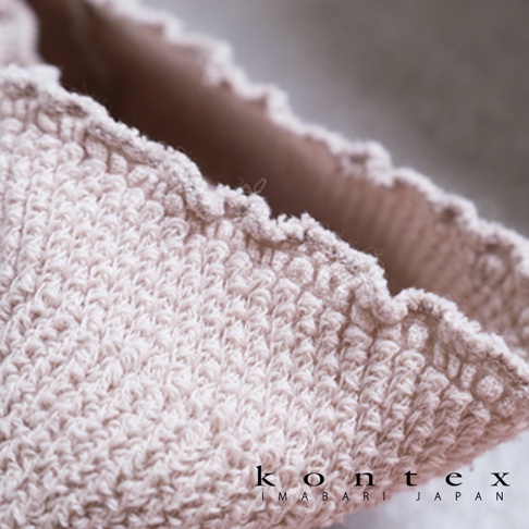 今治萬用彈性枕套，淺粉色，織紋細緻，觸感柔軟，邊緣帶有波浪狀滾邊，品牌標誌印於右下角。