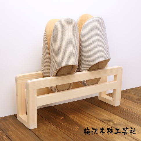 簡約的淺木色木製拖鞋架，架上擺放兩雙由淺棕色和白色細條紋布料製成的拖鞋，拖鞋的內裡為淺棕色。