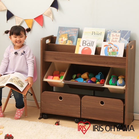 深棕色木質繪本收納架，附有三個置物層，頂層展示多本繪本，中間層有三個淺色收納盒，裝有彩色積木和玩具，底層為兩個附有圓形把手的抽屜，收納架下方裝有四個黑色輪子。