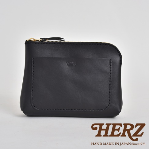 黑色皮革製成的手拿包，正面有縫線裝飾的方形口袋，上方有拉鍊開合，品牌標誌壓印在口袋中央。