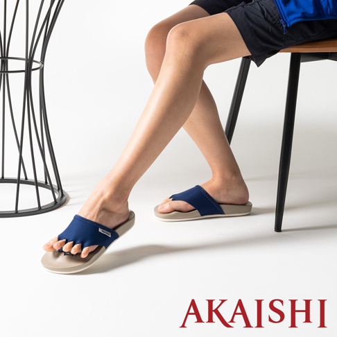 一雙深藍色織物面料的五指訓練美腿拖鞋，米色鞋底，露出腳趾。