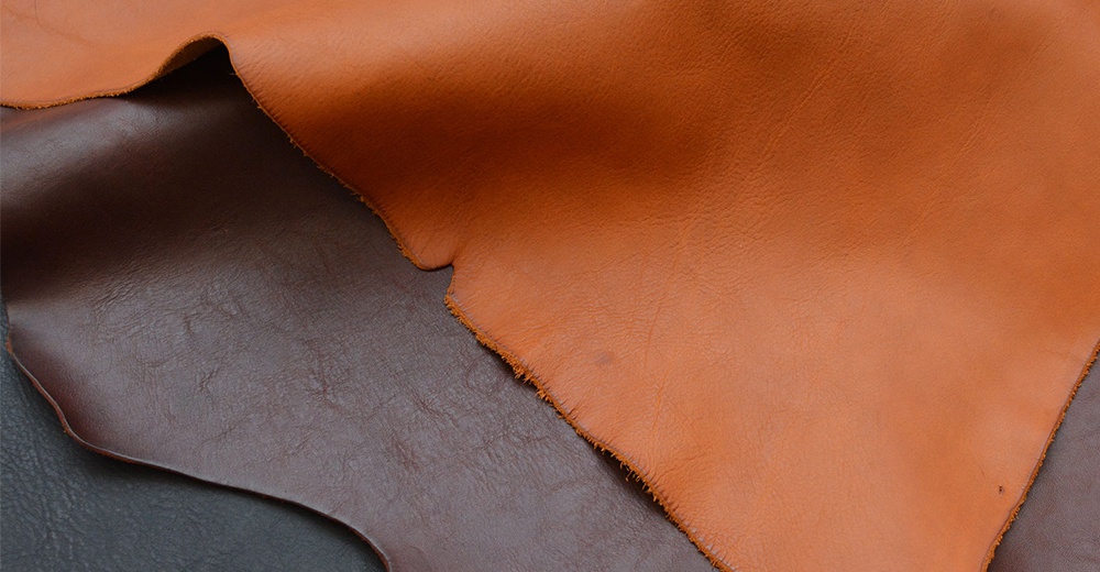 兩塊皮革材質，一塊為淺棕色，另一塊為深棕色，兩塊皮革的表面紋理清晰可見，淺棕色皮革邊緣有毛邊處理。