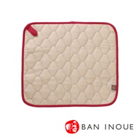 米色棉織吸水墊，菱形絎縫紋理，紅色滾邊，頂部有紅色掛繩，右下角有品牌標誌。