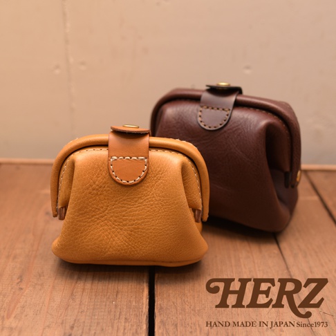 兩款職人手作皮革口金化妝包，一為芥末黃，一為深棕色，皆採用柔軟皮革製作，搭配金屬開合與精緻縫線，展現簡約復古風格。