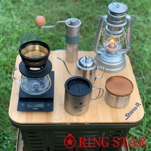 木紋桌面上擺放著咖啡沖泡器具，包括一個玻璃濾杯架、一個金屬濾網、一個玻璃分享壺、一個不鏽鋼細嘴手沖壺、一個不鏽鋼保溫杯，以及一個帶木蓋的儲物罐。背景還有一個汽油燈和一個手搖磨豆機。