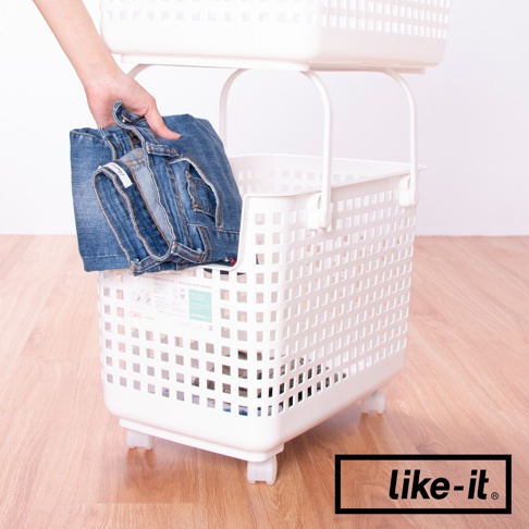 白色雙層塑膠洗衣籃車，底部有輪子。上方籃子裝有摺疊的藍色牛仔褲，由一隻手放入。