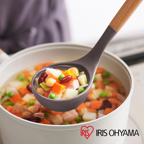 灰色湯勺盛著蔬菜湯，湯內有紅蘿蔔丁、馬鈴薯塊、青豆、玉米粒、雞肉塊及紅豆。湯勺手柄為木質。