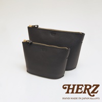 兩款黑色皮革三角收納包，一前一後擺放，皆有金色拉鍊和皮質拉頭，包身表面壓印有品牌標誌。