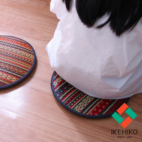 兩個圓形藺草紋織坐墊，一個有紅色、綠色、藍色及米色條紋，另一個有紅色、橘色、紫色及米色條紋，邊緣皆以藍色布料包邊。