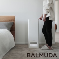 The Pure 空氣清淨機，白色直立式機身，設有簡潔的進氣口，位於臥室地板上，旁邊是木製床頭和床鋪，一位身著白色上衣、黑色長褲的女士正伸手觸碰機身。