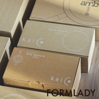 多個紙盒堆疊，其中一個標有「ambai 玉子燒」，另一個標有「milk pan S 0.92L」，還有一個標有「drip kettle S 0.95L」，均為卡其色紙盒，印有白色文字和圖案。