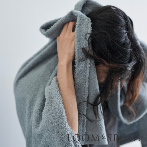 一位人士用灰色蓬鬆毛巾擦拭頭髮，毛巾質感柔軟，呈現出舒適的居家氛圍。