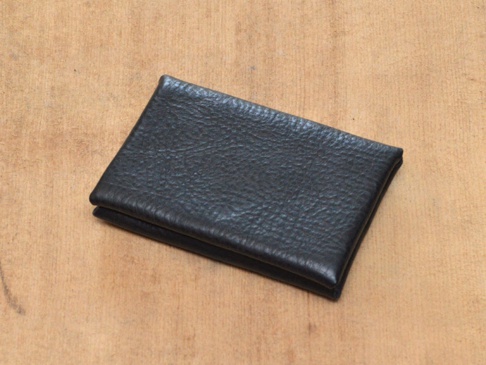 職人手作黑色皮革Organ雙開卡片收納夾，表面有細緻紋理，置於淺棕色木質背景上。