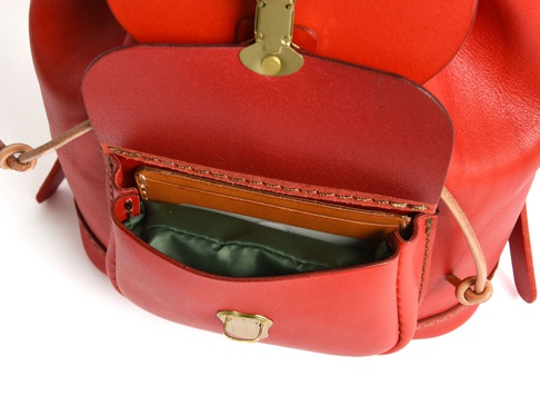 紅色皮革迷你後背包，前袋內有卡片夾層，搭配綠色內襯，袋蓋上有金色鎖扣，肩帶處有皮革繩結裝飾。