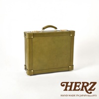 橄欖綠皮革手提行李箱，附有金色金屬扣和皮革提把，箱體四角及邊緣有縫線裝飾，風格簡潔。