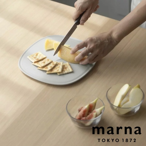 marna TOKYO 1872，一個人在木桌上用刀切著起司，旁邊擺著餅乾、水果切片。