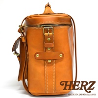 職人手作皮革大型三用旅行後背包，呈現自然棕色皮革，帶有黃銅色金屬扣環和拉鍊，以及清晰的白色縫線。包身設計簡潔，側面有可調節的皮帶和扣子。