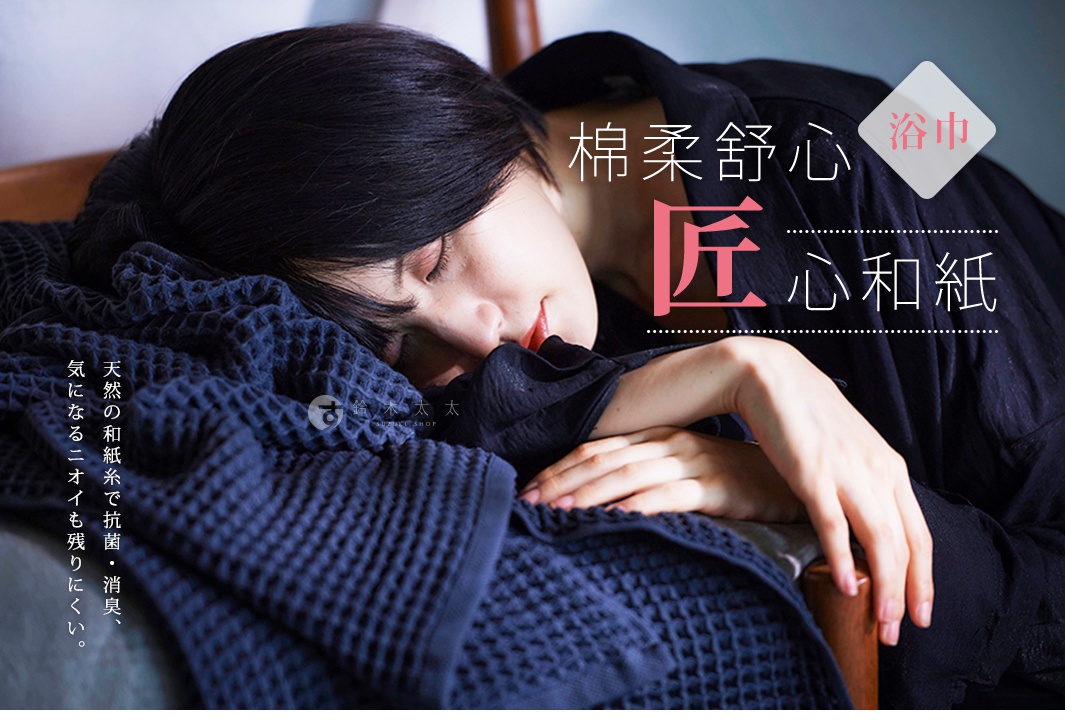 模特兒倚靠在深藍色紋理狀織物上，閉眼休息，臉部表情放鬆，織物觸感柔軟。圖片上方有日文文字，其中「浴巾」字樣被標示出來。