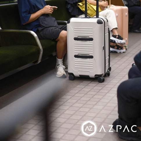 AZPAC Trucker 2.0 20吋煞車防爆行李箱，白色硬殼材質，設有雙層提把和四輪萬向設計，表面有橫向條紋和兩條黑色凹槽。