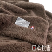 一條深棕色、柔軟的毛巾被，表面有細緻的絨毛紋理。毛巾被上縫有一塊銀色標籤，上面印有「HOTEL'S」字樣和「MADE IN JAPAN」的字樣，以及一個小巧的紅色、白色和藍色組成的徽標。
