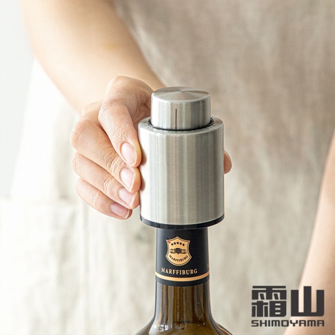一只手正在將一個銀色 304 不鏽鋼真空酒瓶塞插入酒瓶。瓶塞頂部有時間紀錄刻度，整體呈現拉絲金屬質感。