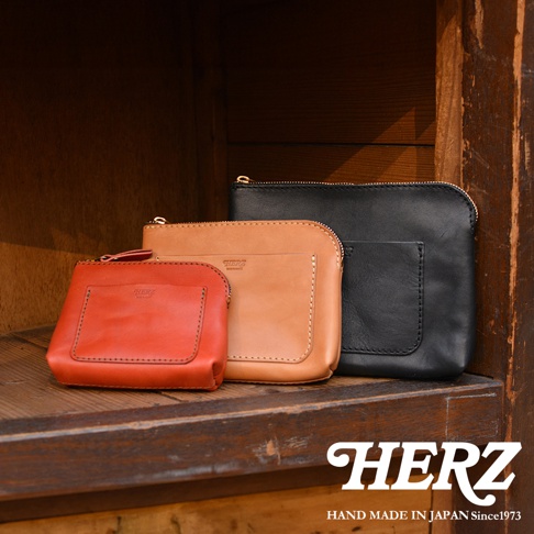 三款職人手作皮革小物收納包，分別為紅色、棕色及黑色，皆為拉鍊開合設計，表面有燙金品牌Logo。