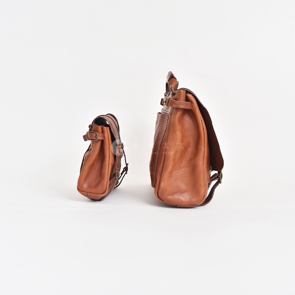 兩款復古棕色皮革水洗加工郵差包，一側為較小的包款，另一側為較大的包款，均設有皮帶與金屬扣環。