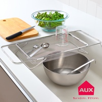 不鏽鋼伸縮瀝水籃，置於水槽上方，籃內有兩個量匙和一個量杯，籃外有一個鋼盆和湯勺。