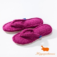 一雙桃紅色竹棉混紡材質的人字夾腳室內拖鞋，鞋面有毛絨質感，配有藍色和橘色的品牌標籤。