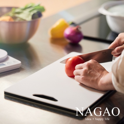 白色雙面抗菌耐熱砧板，上面放著一顆紅番茄，旁邊有黃甜椒、紅洋蔥和一碗蔬菜，以及一個電子秤。