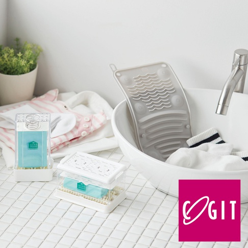 COGIT 品牌多功能軟式洗衣板，搭配洗衣皂及嬰幼兒衣物，擺放在白色格紋檯面上，旁邊是洗手台與水龍頭。