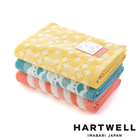 疊放的三條今治浴巾，由上至下分別為黃色、藍色及橘色。黃色浴巾飾有白色傳統紋樣，藍色浴巾帶有白色點狀圖案，橘色浴巾則為白色條紋。材質皆為毛巾布。