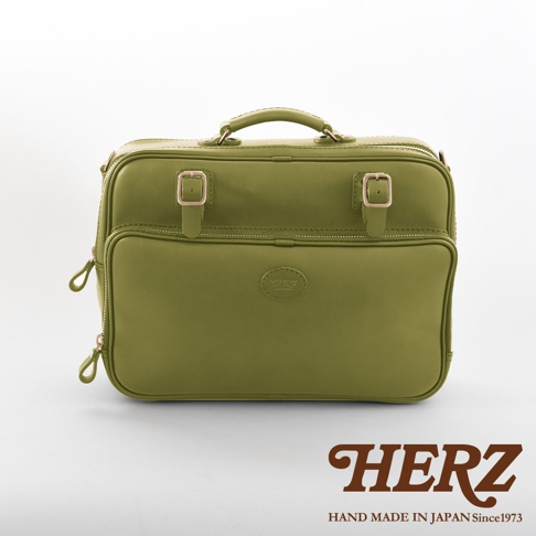 橄欖綠皮革製成的職人手作兩用商務公事包，有頂部提把、兩個金色金屬釦和拉鍊開口，正面有一個圓形皮革壓紋標誌，以及兩個拉鍊式外袋。