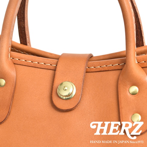 職人手作皮革迷你托特包 T-11，展示包款的棕褐色皮革材質、車線細節、金色金屬釦及提把。