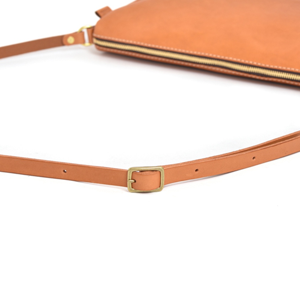 皮革肩背包的長度調節帶，帶有金色扣環。