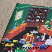 無框帆布藝術海報，描繪聖誕老人的玩具工作室。畫面呈現綠色背景，有擺放著各種玩具的紅色櫃子，紅色抽屜櫃上放著花瓶和燭台。地板上散落著紅綠相間的禮物盒、藍色汽車、綠色恐龍、白色鯨魚、搖搖馬等玩具，以及燈塔和聖誕老人玩偶。畫風溫馨童趣，色彩豐富。