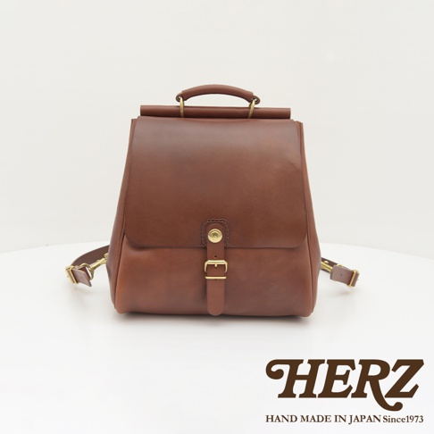 職人手作皮革屋瓦風後背包，咖啡色，採用光滑皮革製成，配有金色金屬扣環和可調節的肩帶。