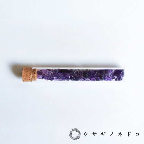 玻璃試管瓶裝有碎裂的紫色礦石，瓶口以軟木塞封住。