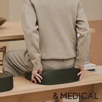 深綠色低反發美姿支撐坐墊，由織物製成，呈彎月形，提供腰部支撐，置於木製表面上。