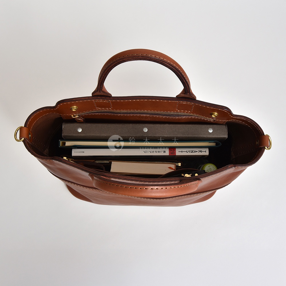 職人手作皮革大容量兩用托特包 T-8，深棕色皮革，包內裝有數本書籍、筆記本與小物品，展現其寬敞的收納空間。