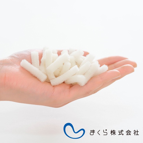 手掌中盛放著大量白色、細長、圓柱狀的鬆軟填充物，材質類似海綿或纖維，用於枕頭或抱枕。