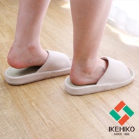 一雙淺米色藺草透氣室內拖鞋，鞋面為織紋材質，鞋底為藺草編織，展示於木質地板上。