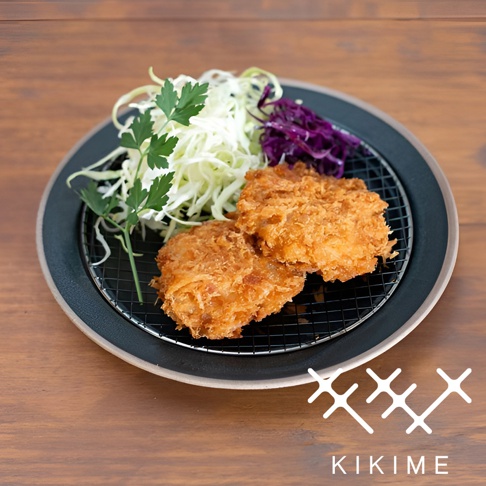 美濃燒瀝油餐盤，盤身為深灰色，內襯黑色瀝油網架，盛有兩塊金黃酥脆的炸物，搭配切絲的白色高麗菜、紫高麗菜及綠色香草。