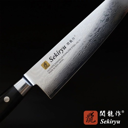 VG10不鏽鋼33層大馬士革三德刀，刀刃展現經典水波紋路，銀色金屬光澤，黑色手柄，刀身上印有「Sekiryu」品牌標誌與「MADE IN SEKI-JAPAN」字樣，整體為專業廚刀設計。
